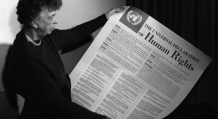 Eleanor Roosevelt reading the poster sized version of the Commission on Human Rights.